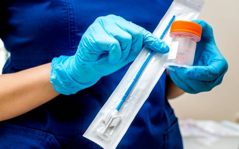 Nurse holding a speculum and cup used in a cervical screening