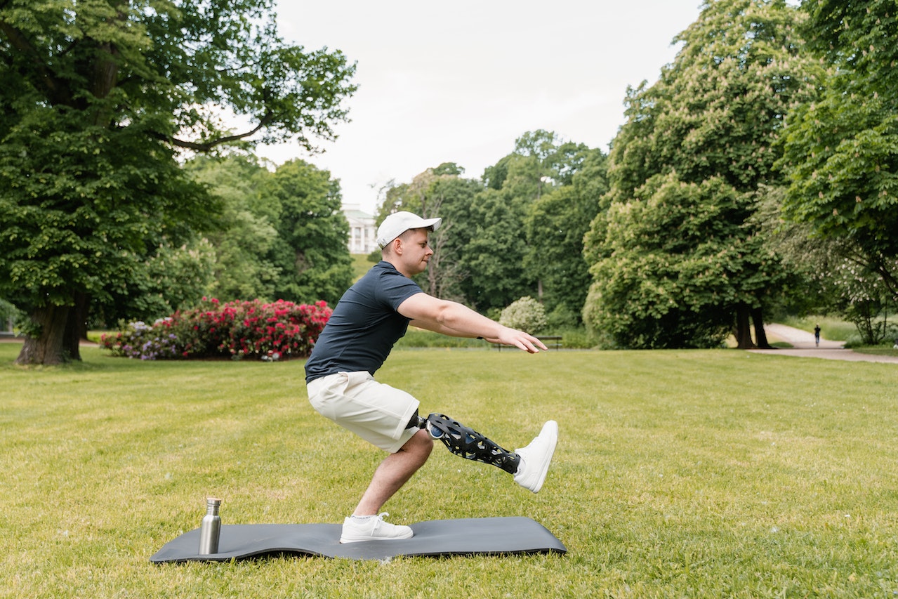 Man is doing an exercise activity on a mat in a park