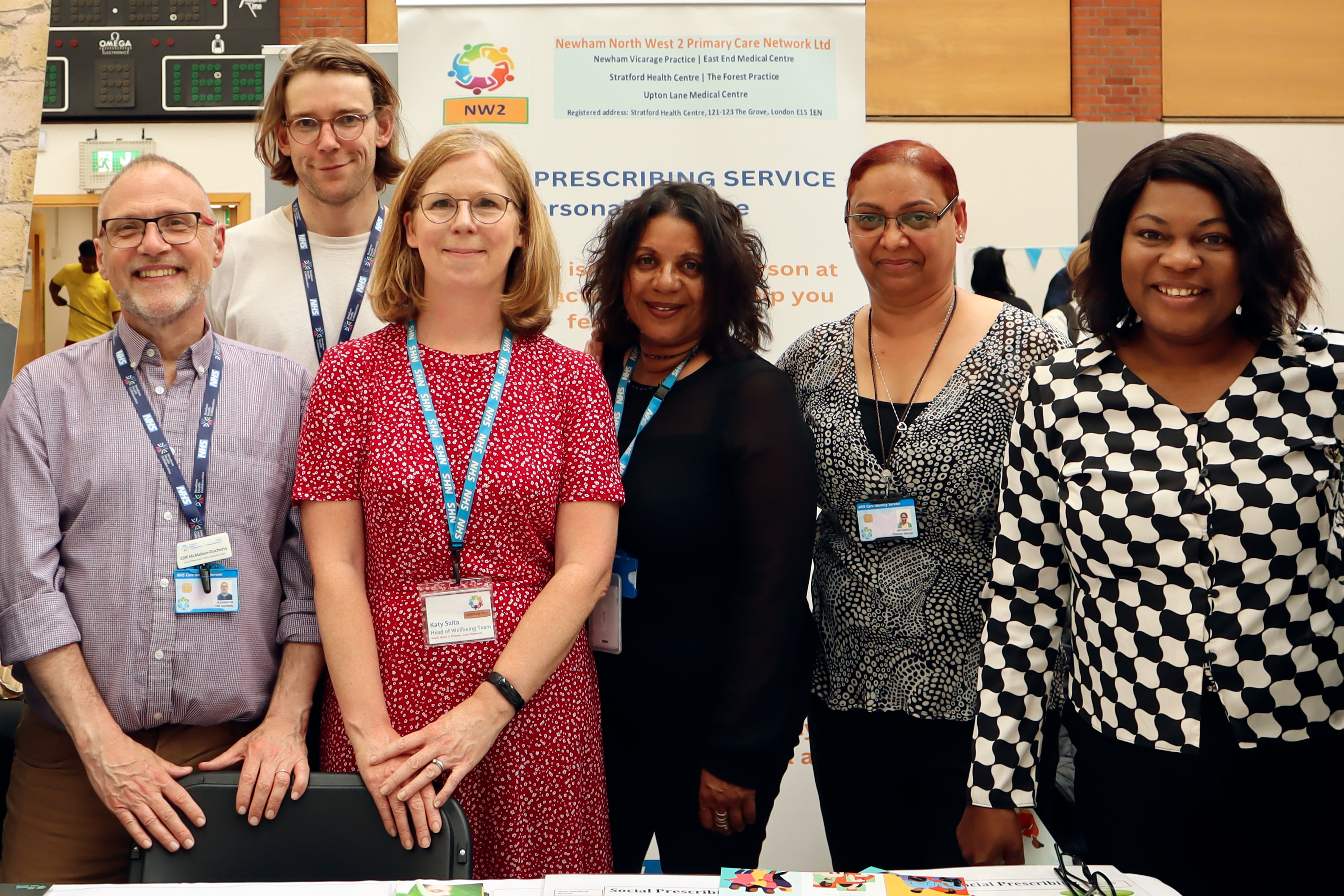 A group of social prescribers at a stall at a community event smilling together