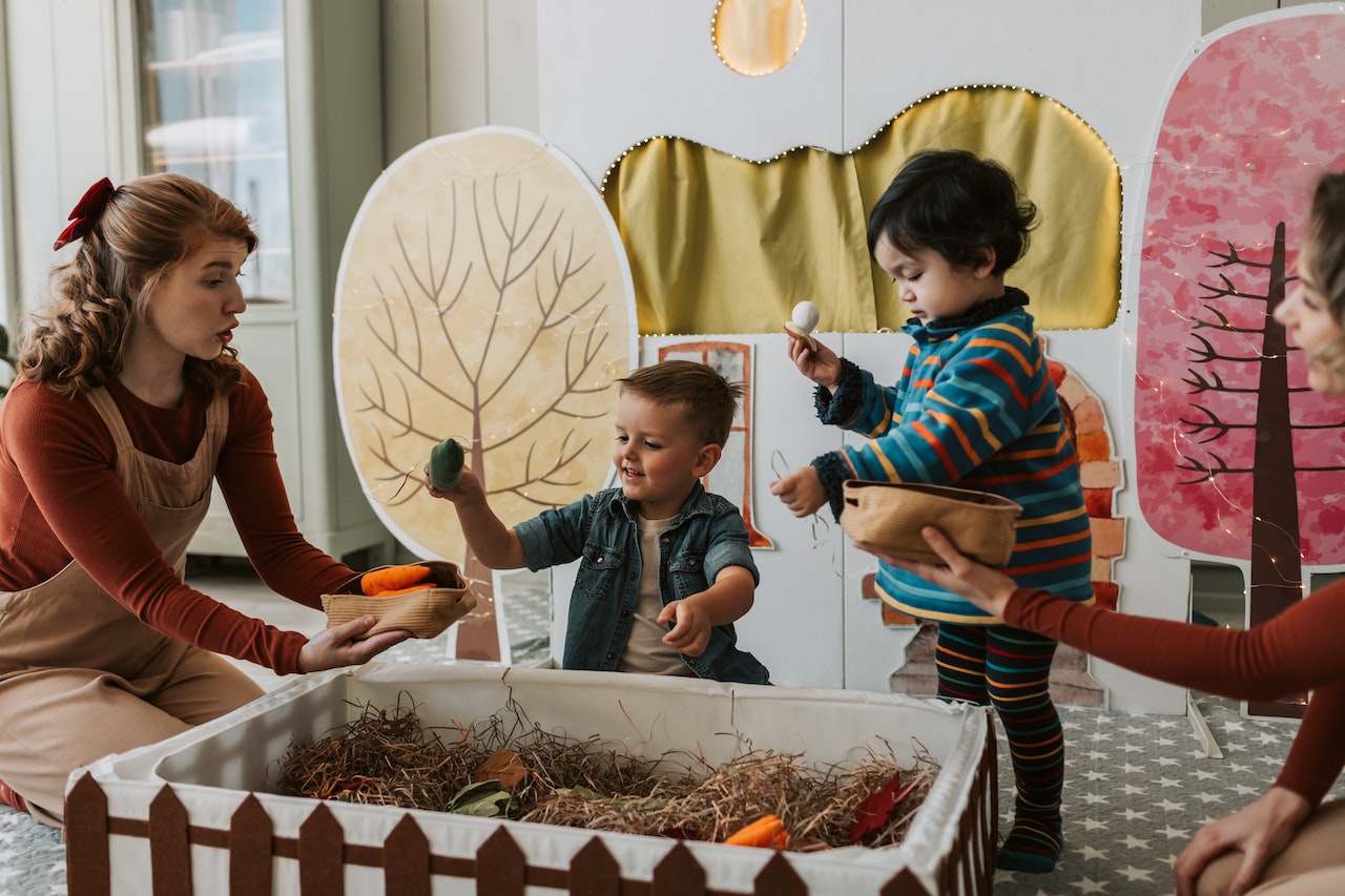 Children playing in a nursery with a nursery worker