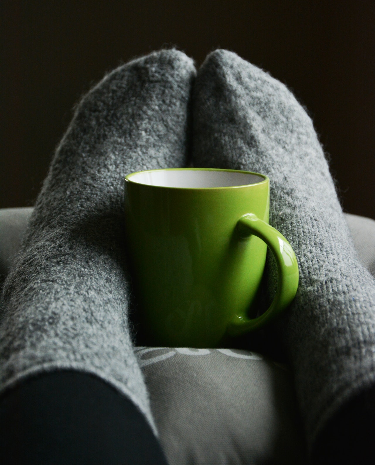 Person with their cosy socks on with a mug of tea