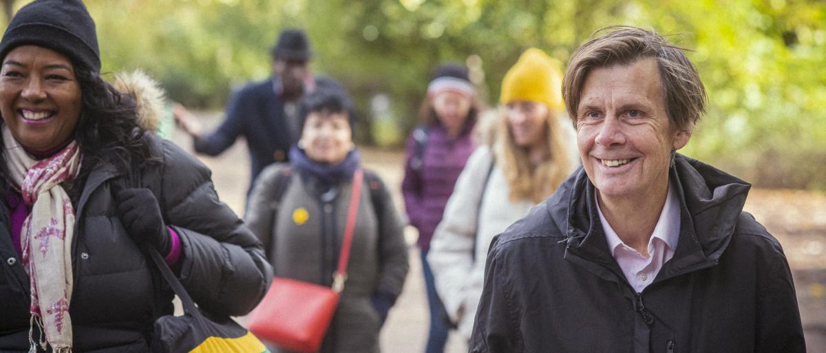 Walking group of people of different ages walking together through a green space