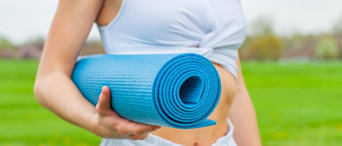 A woman in a park holding a mat