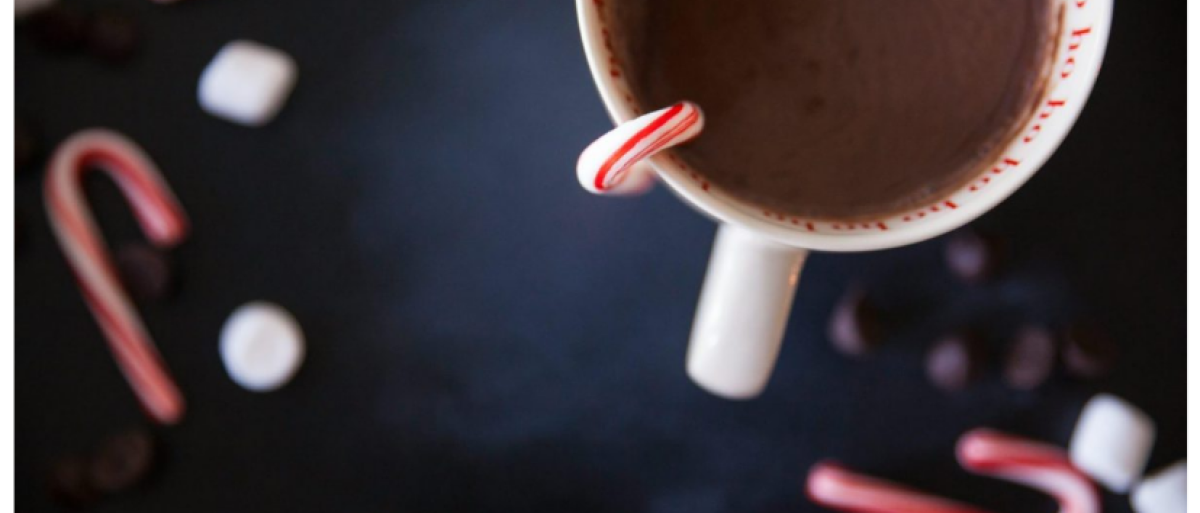 A cup with cocao and white and red candy sticks 