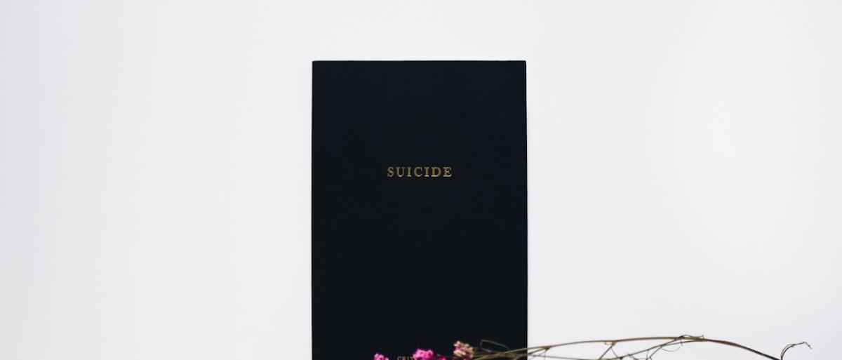 Suicide written on a blackboard with pink flowers