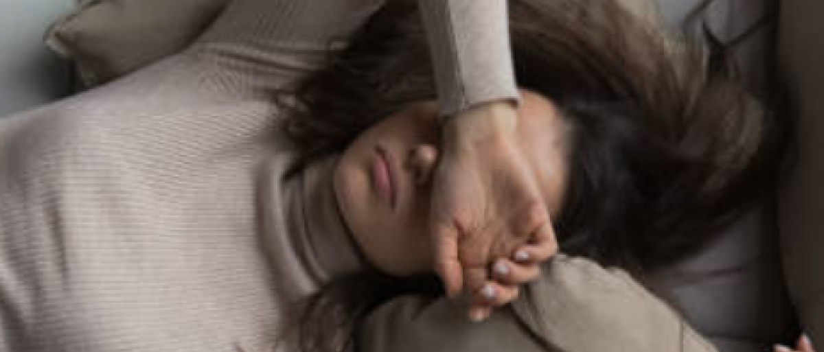 Someone lying down on a couch looking exhausted 