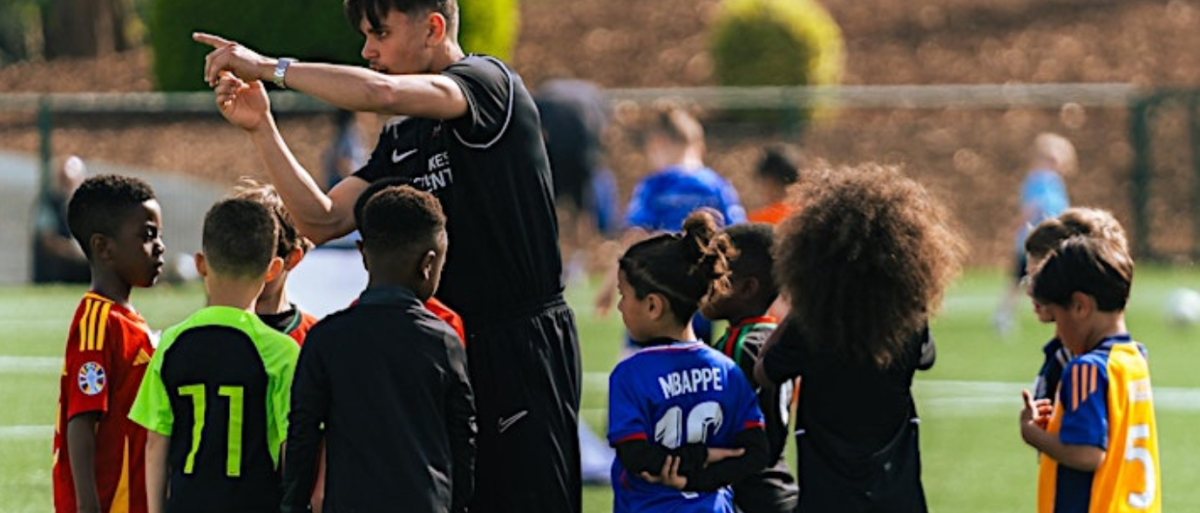 Group of children on a football field with a coach
