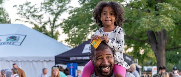 Dad with his daughter on his shoulders at a community event