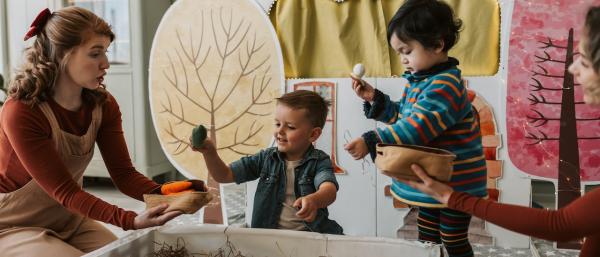Children playing in a nursery with a nursery worker