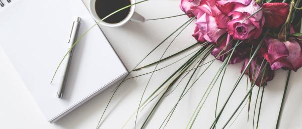Notebook with pen, cup of coffee and flower