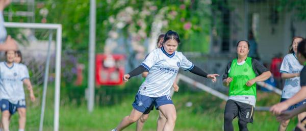 Women and girl playing football