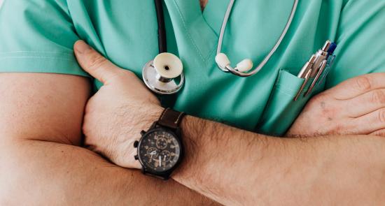 Man in doctors' scrubs crossing his arms