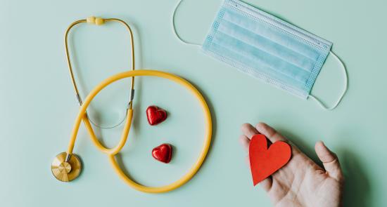 Stethoscope and mask on a blue background with some red hearts