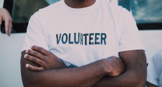 man crossing his arms wearing a white top with volunteer written across it