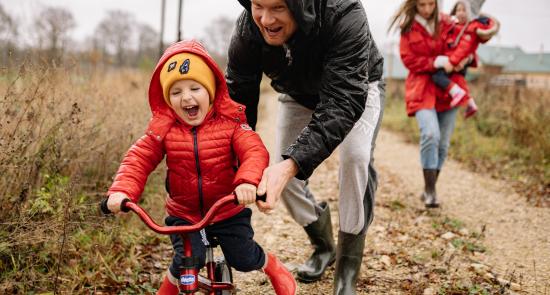 Dad helping young boy to ride a bike