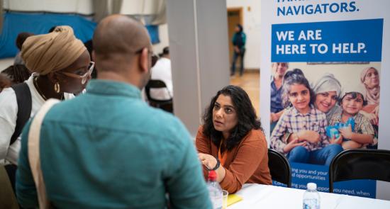 Family Navigator speaks to two colleagues from behind a stall at a fair