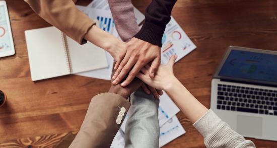 Colleagues putting their hands together in a circle 