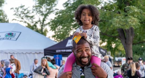 Dad with his daughter on his shoulders at a community event