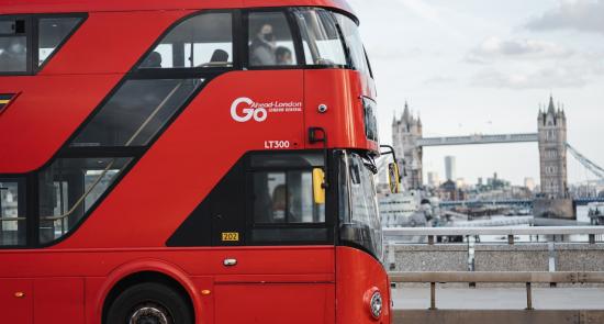 Red London bus driving in front of Tower Bridge