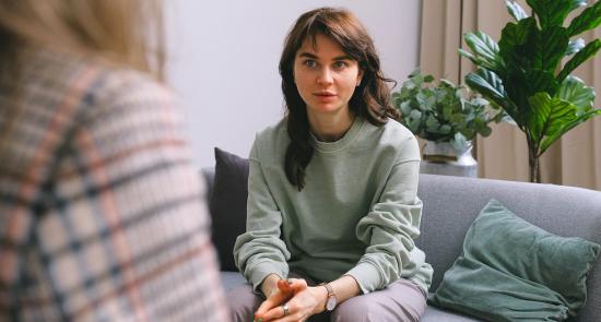 woman sitting on a sofa talking to a support worker