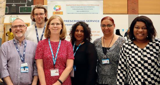 A group of social prescribers at a stall at a community event smilling together