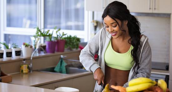 Woman chopping up fruit in the kitchen smiling