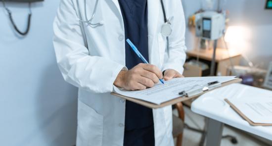 Doctor in a white coat writing on a clipboard