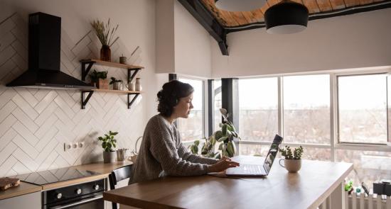 Lady sitting in her kitchen on her laptop