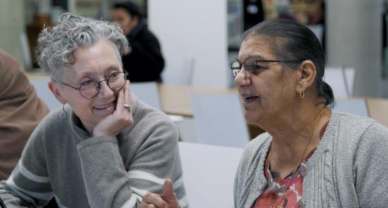 Two women laughing and chatting together at a library event