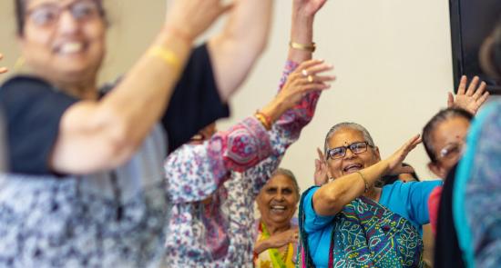 Women doing a seated exercise class together, smiling