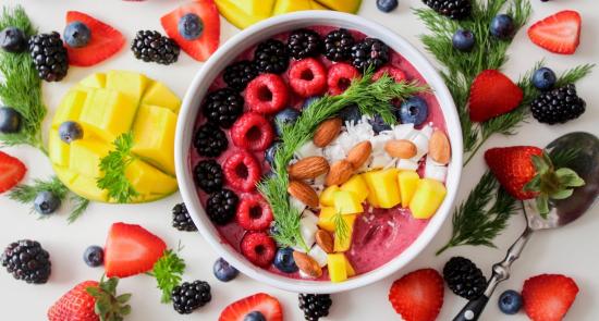 Colourful fruit bowl surrounded by different fruit