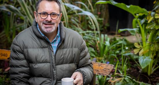Man sat in his garden with a cup of tea smiling