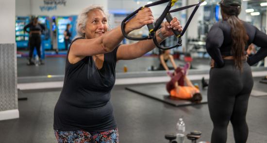Lady using a cable machine at a gym and smiling