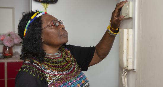 A woman is checking her thermostat in her house