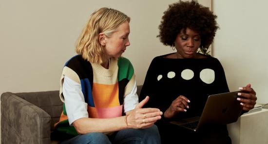 Two women sat together talking as if in a meeting