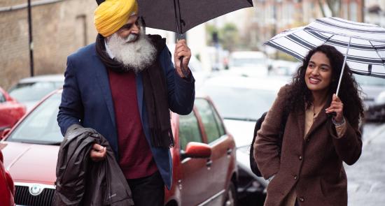 Man and woman walking together in the rain with their umbrellas up