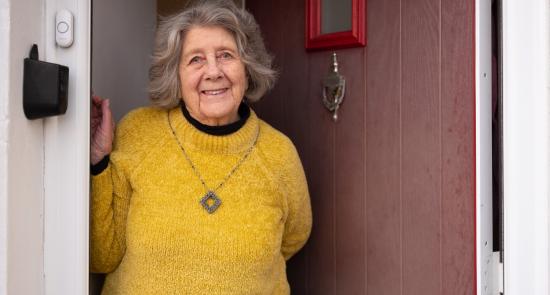 Older woman standing at her frontdoor and smiling