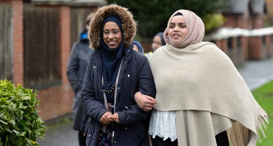 2 women holding hands and walking