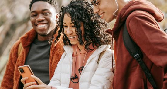 3 Young people looking into a phone smiling